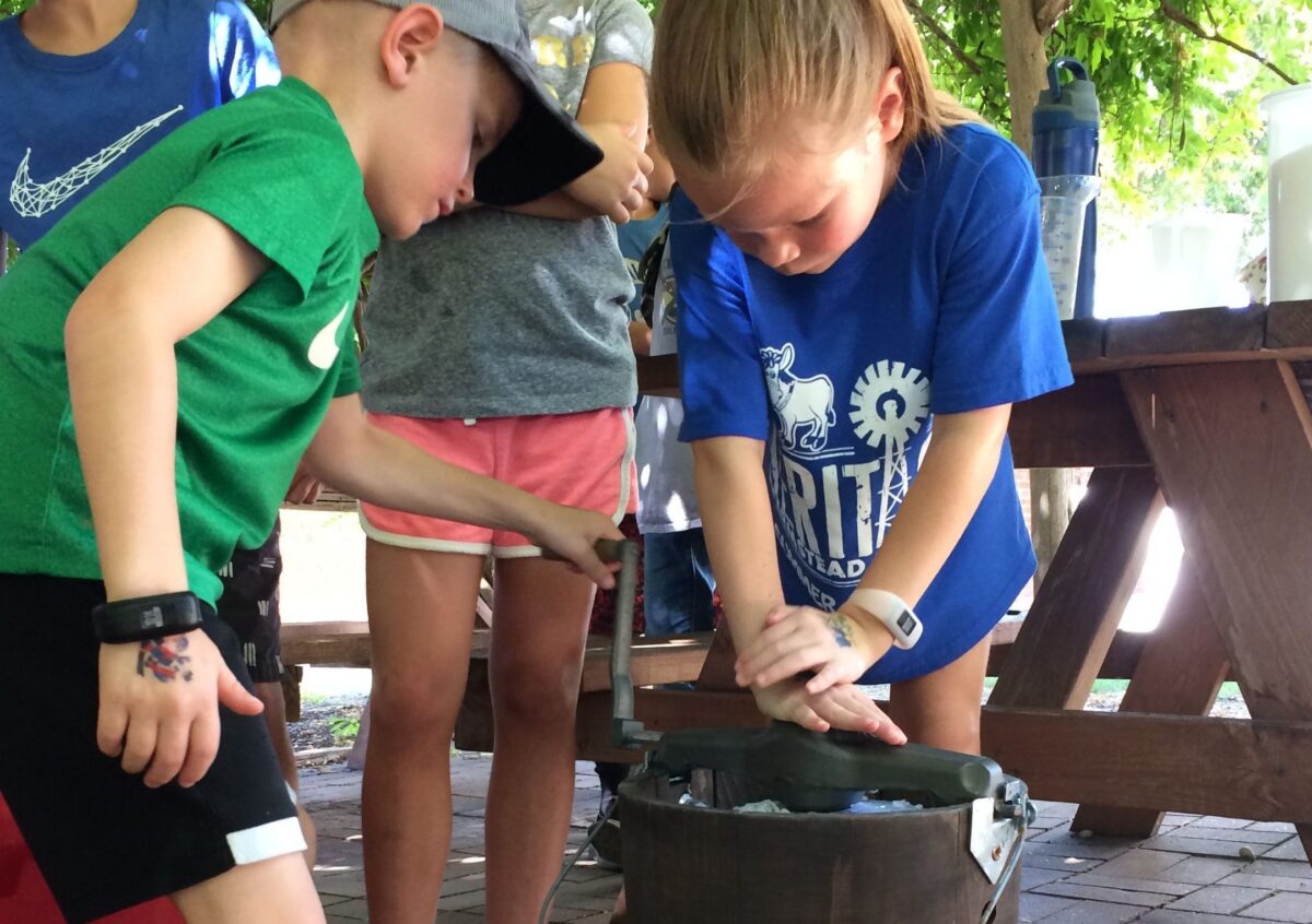 Children churning ice cream at Heritage Farmstead Museum during summer camp